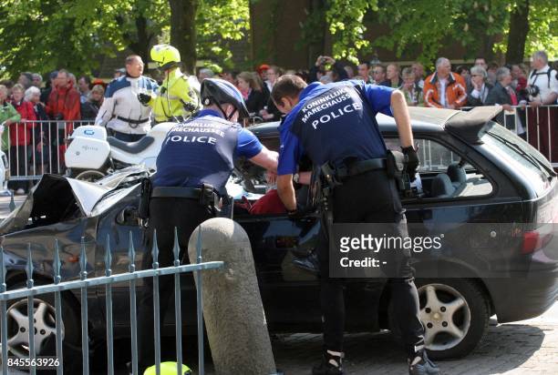 Two policemen attempt to stop the driver after he slammed with his car into Dutch festival-goers in Apeldoorn on April 30, 2009 killing five people...