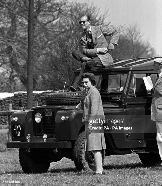 Prince Philip, the Duke of Edinburgh, perches on the roof of a Land Rover but Queen Elizabeth II prefers a ground-level view of competitors during...