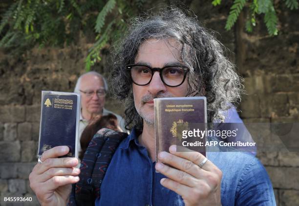 French-Lebanese director Ziad Doueiri, who has been criticised for filming part of a production in Israel, holds up his French and Lebanese passports...