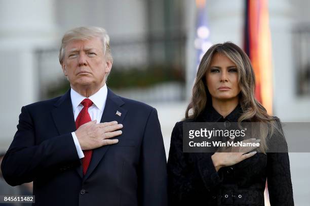 President Donald Trump and first lady Melania Trump place their hands over their hearts on the South Lawn of the White House during the playing of...