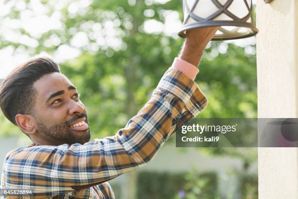 man van de veranderende gloeilamp in huis portiek - fitting stockfoto's en -beelden