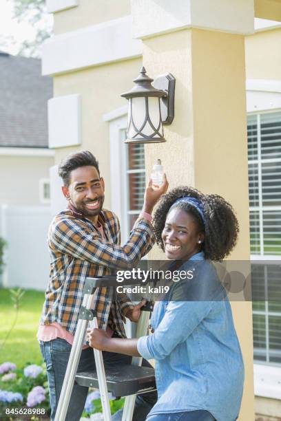 paar buiten huis, wijzigen van de gloeilamp - fitting stockfoto's en -beelden