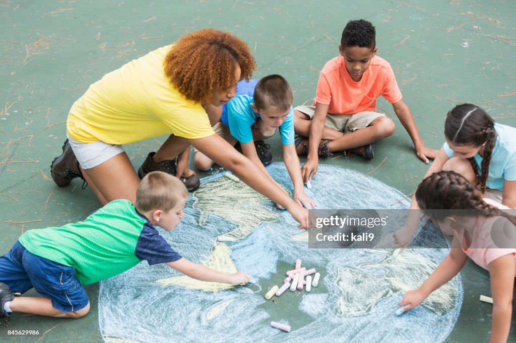 Camp counselor with children, chalk drawing of earth