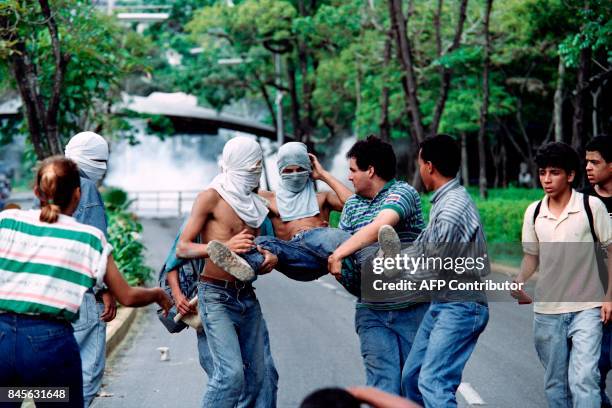 Demonstrators carry a fellow student who was injured by a rubber bullet on June 11, 1992 after police dispersed a small group of protesters near the...