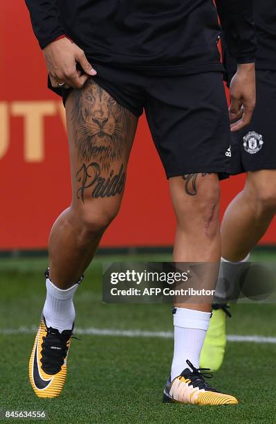 Manchester United's Argentinian defender Marcos Rojo unveils a tattoo as he attends a team training session at the club's training complex near...