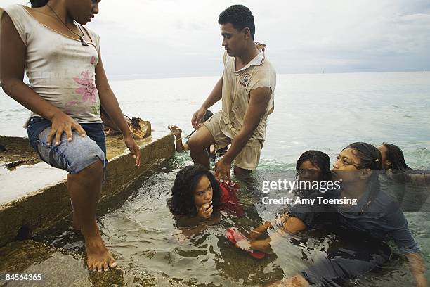 Children play and swim in their clothes off a wharf on April 14, 2007 on the main island of the Ha'api Island chain in Tonga. Tongans are known for...