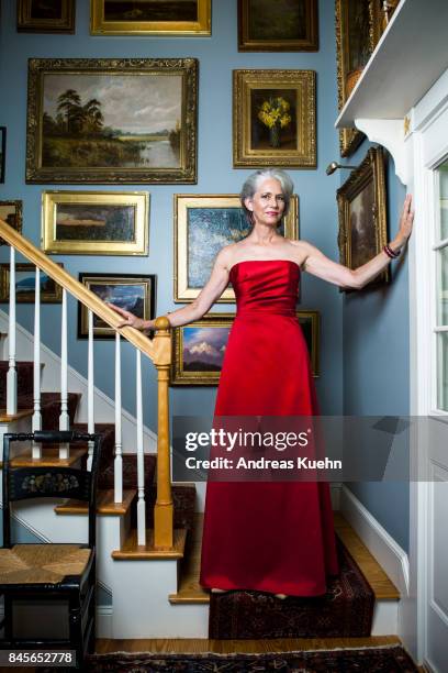 beautiful woman in her late fifties with silvery, grey hair wearing a glamorous, red evening gown while standing in a staircase in front of golden framed oil paintings. - trägerloses abendkleid stock-fotos und bilder