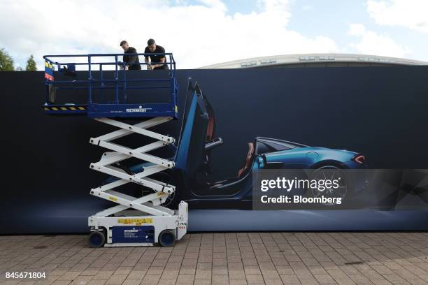 Workers secure a giant advertisement featuring a McLaren 570S Spider luxury automobile, manufactured by McLaren Automotive Ltd., ahead of the IAA...