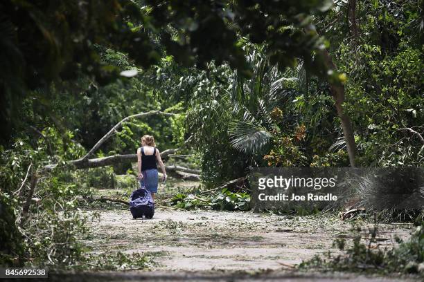 Philippa Regueira returns home through a street littered with downed trees and branches after seeking shelter in a friend's home after Hurricane Irma...