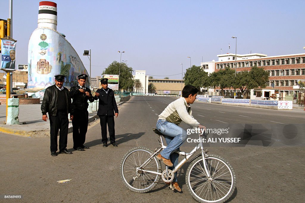 A boy rides his bike as Iraqis police st
