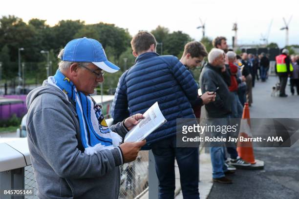 Fan of Huddersfield Town reads the match day programme prior to the Premier League match between West Ham United and Huddersfield Town at London...