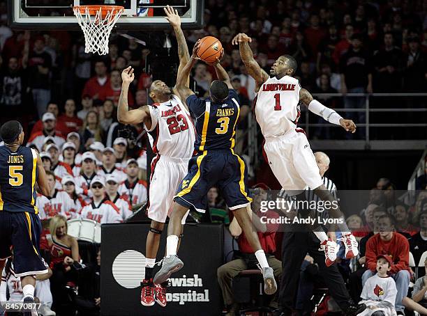 Terrence Jennings and Terrence Williams of the Louisville Cardinals block the shot of Devin Ebanks of the West Virginia Mountaineers during the Big...