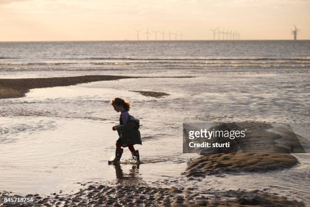 kleines mädchen mit offshore-windpark - girl blowing sand stock-fotos und bilder