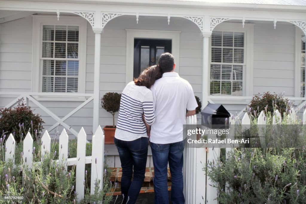 Couple standing in front of their new home.