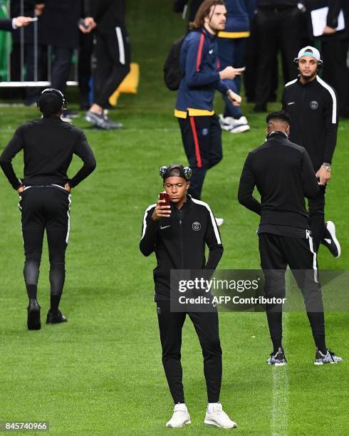 Paris Saint-Germain's French forward Kylian MBappe uses a mobile phone during a walk around the pitch at the Celtic Park in Glasgow, on September 11...