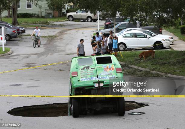 Residents survey the scene of a van in a sinkhole on Monday, Sept. 11 that opened up at the Astor Park apartment complex in Winter Springs, Fla.,...