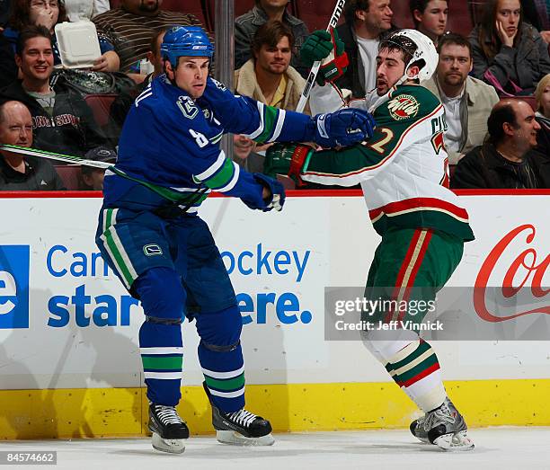 Cal Clutterbuck of the Minnesota Wild gets bumped by Willie Mitchell of the Vancouver Canucks during their game at General Motors Place on January...