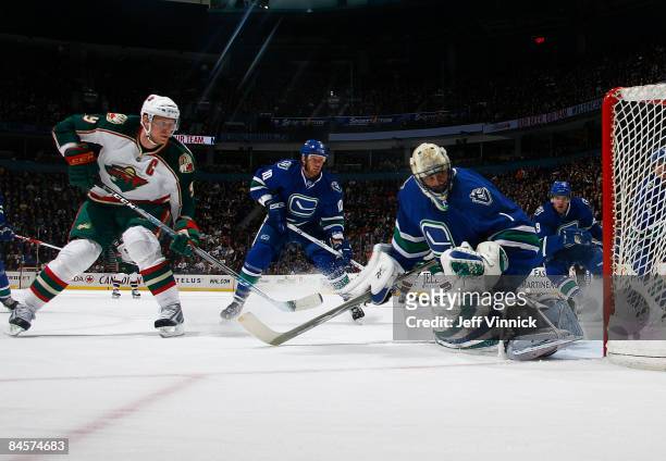 Ryan Johnson of the Vancouver Canucks and Taylor Pyatt watch the puck get by Roberto Luongo off a shot by Mikko Koivu of the Minnesota Wild during...