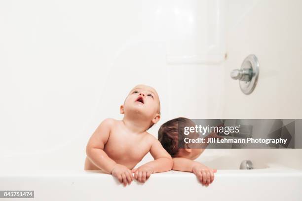 one year old twin boys play in a bathtub together - fraternal twin stock pictures, royalty-free photos & images