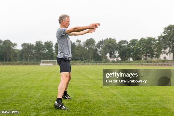 Duelmen, Germany Leisure sports and personal fitness. A man is doing some relaxation exercise after a workout on a sports field. Staged picture on...