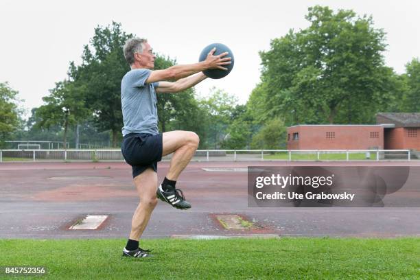 Duelmen, Germany Leisure sports, personal fitness. A man is training leg lift on a sports field. In his hands he holds a medicine ball. Staged...