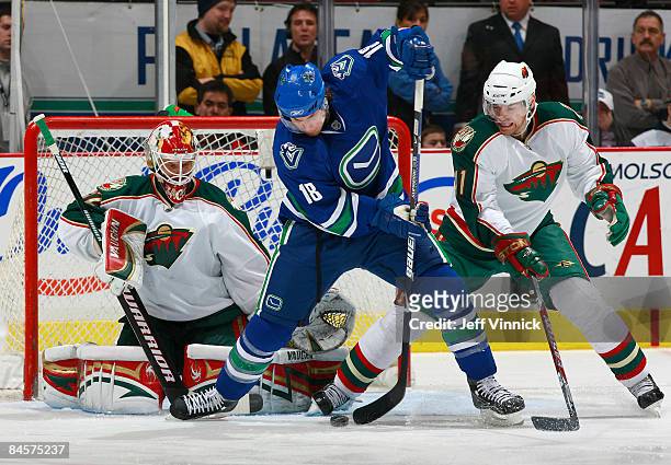 Steve Bernier of the Vancouver Canucks tries to deflect a puck by Niklas Backstrom of the Minnesota Wild with Martin Skoula looking on during their...