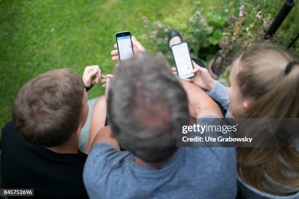 Duelmen, Germany Two teenagers and their father are busy with their smartphones. Staged picture on August 10, 2017 in Duelmen, Germany.