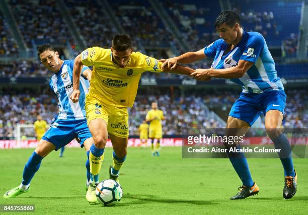 Jonathan Calleri of Union Deportiva Las Palmas competes for the ball with Federico Ricca of Malaga CF and Diego Gonzalez of Malaga CF during the La...