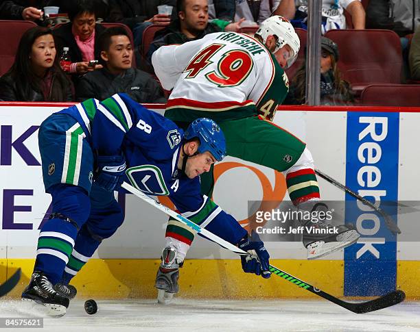 Willie Mitchell of the Vancouver Canucks and Dan Fritsche of the Minnesota Wild battle for the puck during their game at General Motors Place on...