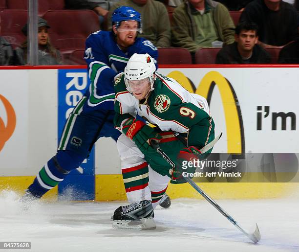 Mikko Koivu of the Minnesota Wild is hooked by Daniel Sedin of the Vancouver Canucks in overtime of their game at General Motors Place on January 31,...