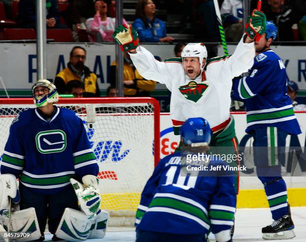 Owen Nolan of the Minnesota Wild celebrates the winning goal in overtime as Roberto Luongo, Ryan Johnson and Willie Mitchell of the Vancouver Canucks...