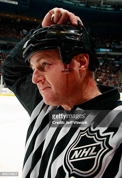 Linesmen Lonnie Cameron sports a cut on his cheek after getting hit by a puck during the game between the Vancouver Canucks and the Minnesota Wild at...