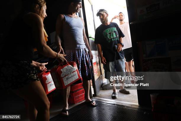 Employees at a 7-Eleven sell a limited amount of groceries to desperate customers following the loss of electricity and the closing of most stores in...