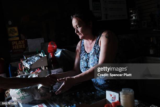 Andrea Conway, and employee at a 7-Eleven, sells a limited amount of groceries to customers following the loss of electricity and the closing of most...