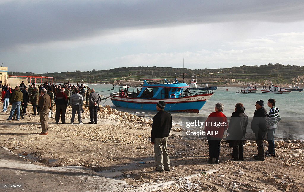 Local people (R) watch would-be immigran