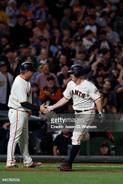 Ty Blach of the San Francisco Giants is congratulated by third base coach Phil Nevin after hitting a three run home run against the Oakland Athletics...