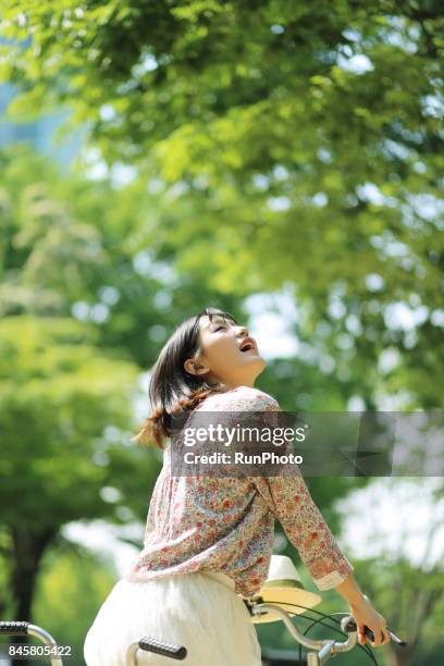 woman riding a bicycle and enjoying nature - three-quarter-rear-view stock pictures, royalty-free photos & images