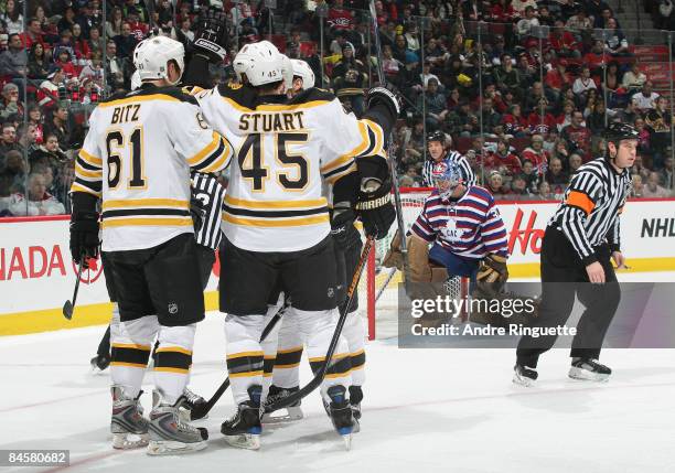 Carey Price of the Montreal Canadiens pulls the puck out of the net as Byron Bitz and Mark Stuart of the Boston Bruins celebrate a second period goal...