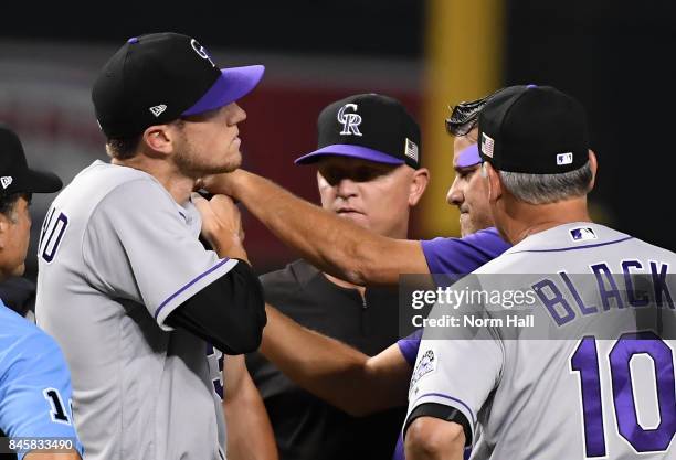 Head trainer Keith Dugger of the Colorado Rockies looks at pitcher Kyle Freeman after being hit by a line drive off the bat of JD Martinez of the...