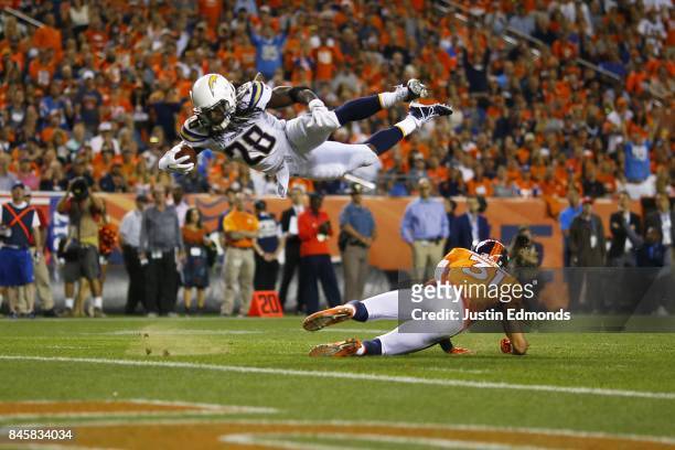 Running back Melvin Gordon of the Los Angeles Chargers dives over strong safety Justin Simmons of the Denver Broncos in the second quarter at Sports...