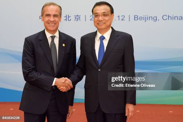 Chairman Mark Carney of the G20's Financial Stability Board shakes hands with Chinese Premier Li Keqiang before The 1+6 Round Table Dialogue meeting...