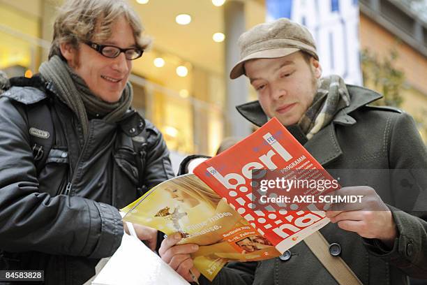 Two men study the festival program as they queue to buy tickets for the 59th Berlin International Film Festival in Berlin on February 2, 2008....