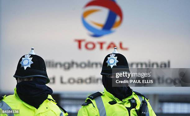 Police officers watch protesters at the Lindsey Oil Refinery, near Immingham, north east England, on February 2, 2009. Wildcat strikes against...