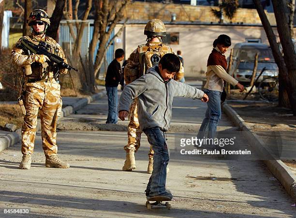 Afghan kids skateboard near their homes along side British ISAF soldiers on patrol on February 02, 2009 in Kabul, Afghanistan. After decades of war...