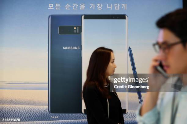 Attendees walk past an advertisement for the Samsung Electronics Co. Galaxy Note 8 smartphone during a media event in Seoul, South Korea, on Tuesday,...