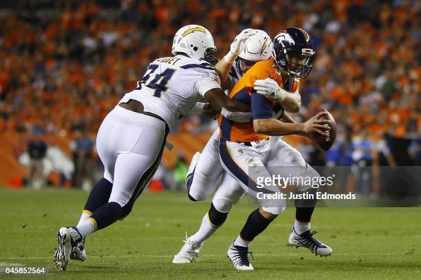Quarterback Trevor Siemian of the Denver Broncos is tackled by Corey Liuget and defensive end Joey Bosa of the Los Angeles Chargers in the third...