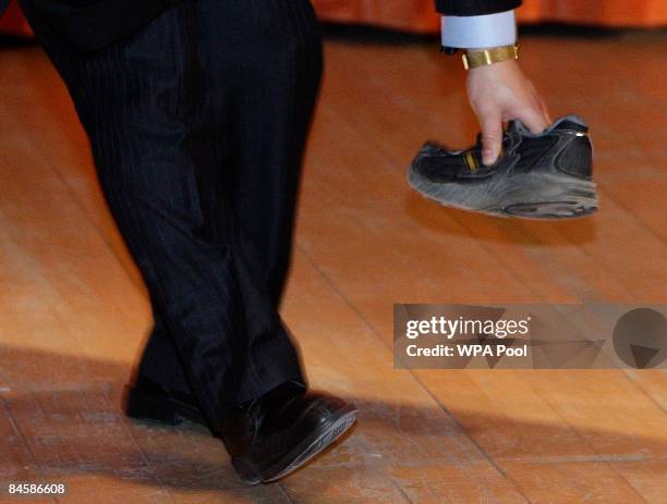 Security guard picks up a shoe that was thrown towards Chinese Premier Wen Jiabao as he delivered a speech at the University of Cambridge on February...