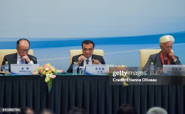 Chinese Premier Li Keqiang holds his glasses as he sits between President Jim Yong Kim of the World Bank and Managing Director Christine Lagarde of...
