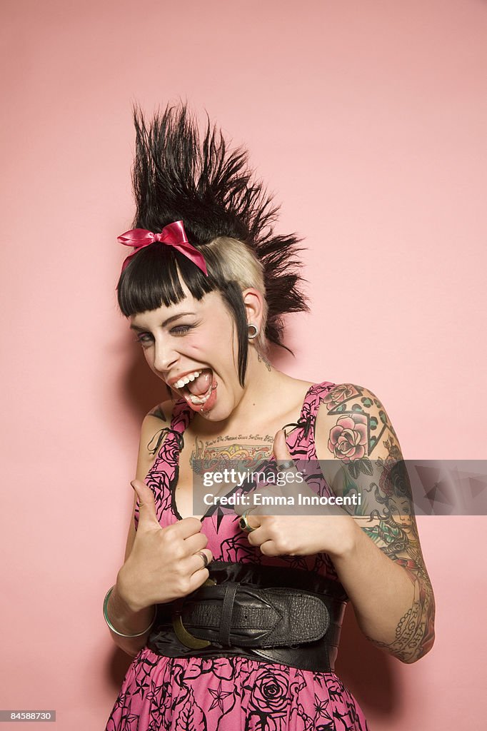 Young woman with tattoos giving the thumbs-up