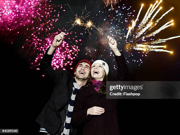 couple holding sparklers at firework display - fire works stock pictures, royalty-free photos & images